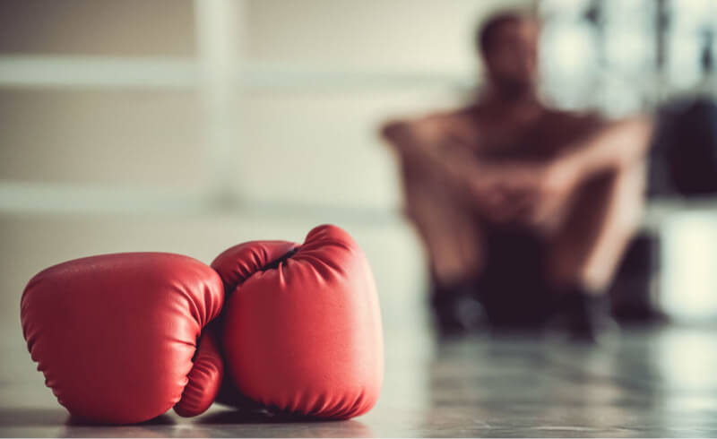 red boxing gloves and boxer sitting 