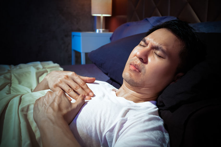 man with heartburn lying in bed